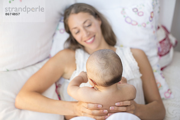 Mutter hält Baby Junge auf Bett