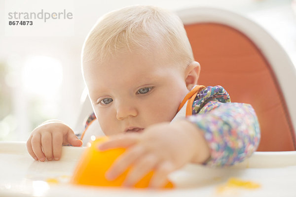 Kleines Mädchen spielt mit Gelatine-Dessert im Hochstuhl