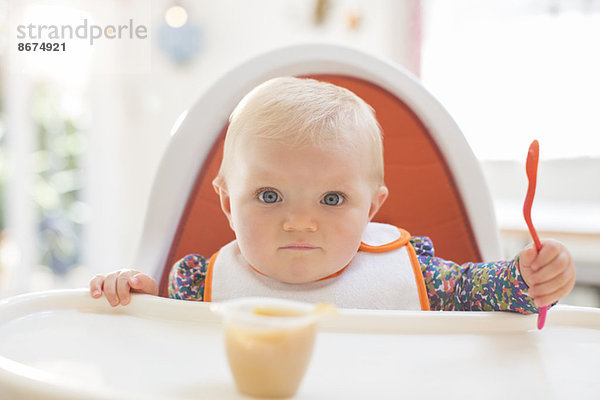 Baby Mädchen beim Essen im Hochstuhl