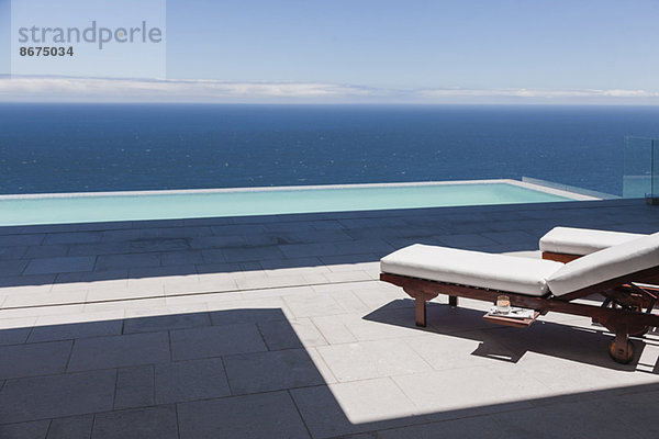 Liegestühle und Infinity-Pool mit Blick auf das Meer
