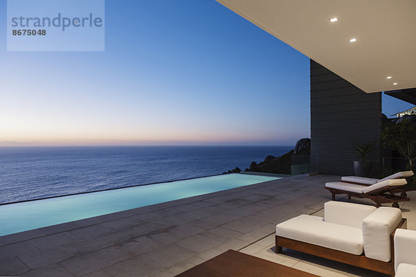 Moderne Terrasse und Infinity-Pool mit Blick auf das Meer bei Sonnenuntergang