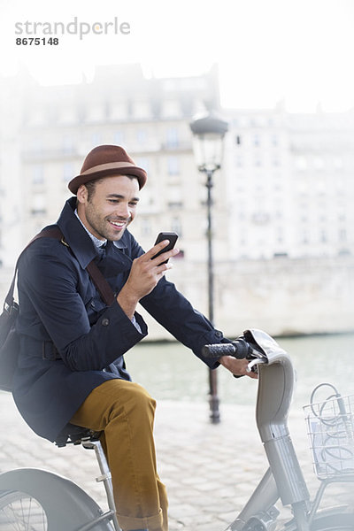 Geschäftsmann mit Handy auf dem Fahrrad entlang der Seine  Paris  Frankreich