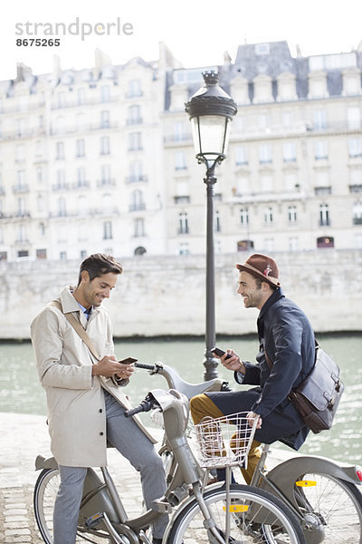 Geschäftsleute mit Mobiltelefonen auf Fahrrädern entlang der Seine  Paris  Frankreich