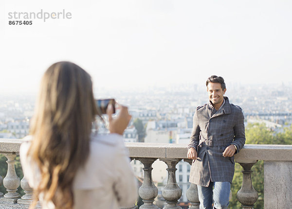 Frau fotografiert Freund mit Paris im Hintergrund