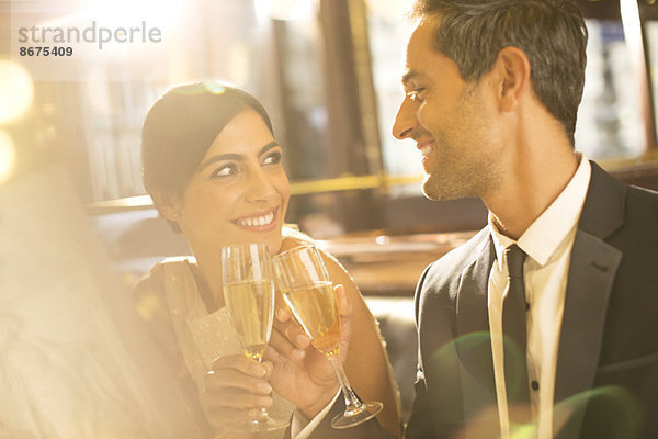 Gut gekleidetes Pärchen toastet Champagnerflöte im Restaurant