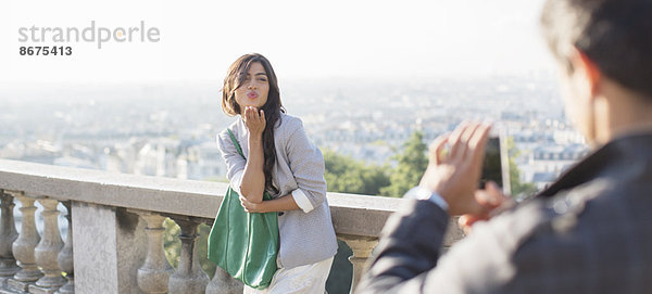 Mann fotografiert Freundin mit Paris im Hintergrund