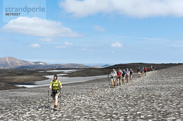 Trekking im Hochland  Wandergruppe wandert hintereinander auf Pfad über Schneefeld  Trekkingweg Laugavegur  bei Hrafntinnusker  Rangárþing ytra  Suðurland  Island  Skandinavien