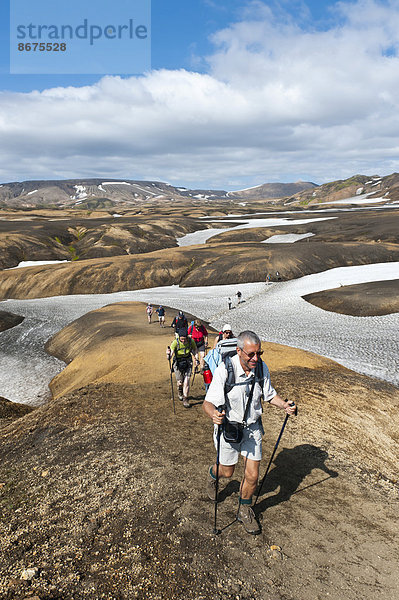 Trekking im Hochland  Wandergruppe auf Pfad über Schneefelder  Trekkingweg Laugavegur  bei Hrafntinnusker  Rangárþing ytra  Suðurland  Island  Skandinavien