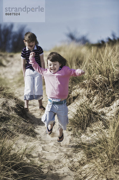 Zwei kleine Kinder spielen in den Dünen.