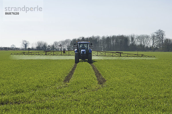 Traktor und Feldspritze auf dem Feld.