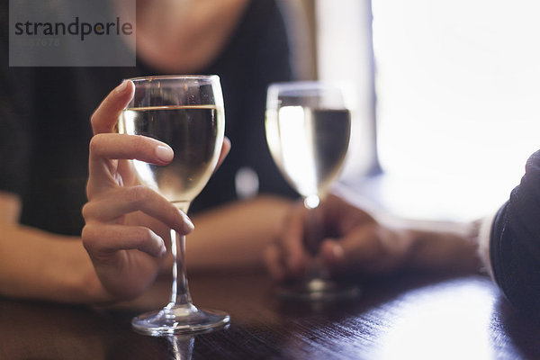Zwei Personen  ein Paar sitzt in einer Bar und trinkt ein Glas gekühlten Weißwein.