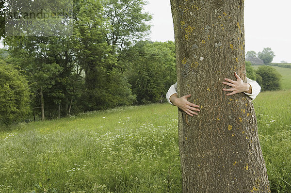 Eine Person  die einen Baum umarmt.