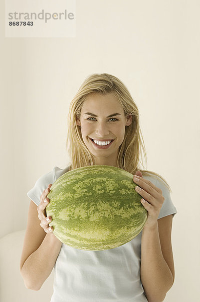 Eine Frau hält eine große grüne Wassermelone in der Hand.