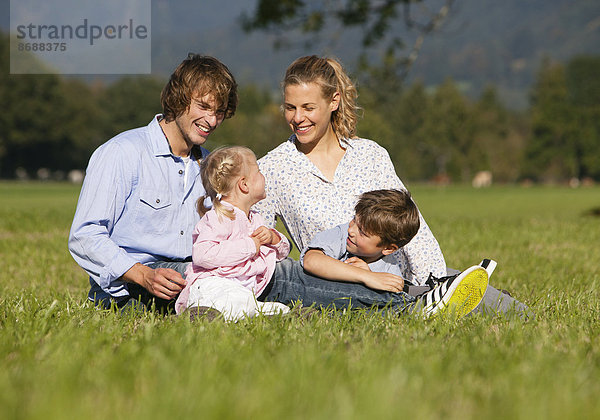 Familie mit zwei Kindern sitzt in Wiese