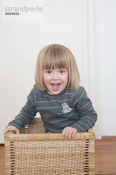 Porträt eines lächelnden kleinen Mädchens im Korb stehend