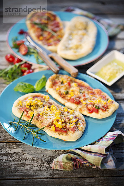 Pizzabrötchen  mit Schinken  Salami  Mozzarella  Tomaten  Rucola  Mais und Oliven