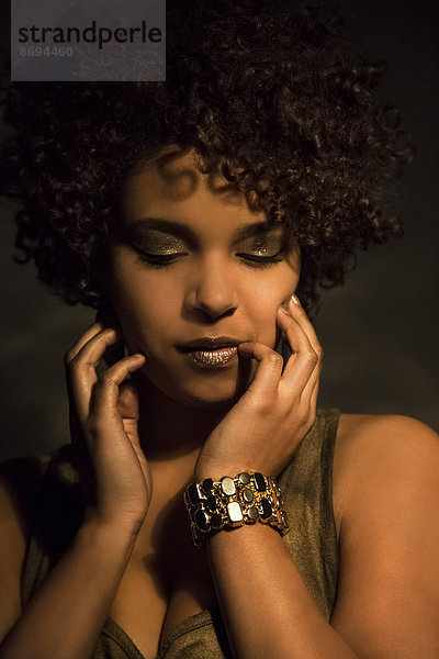 Porträt einer Afro-Amerikanerin mit goldenem Make-up und Armband