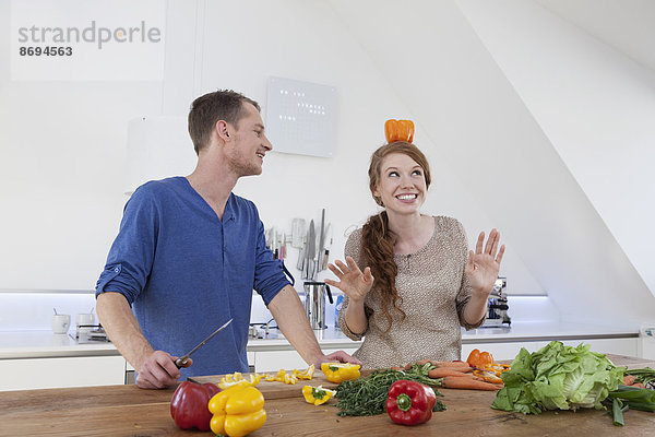 Junge Frau balanciert orangefarbene Paprika auf dem Kopf