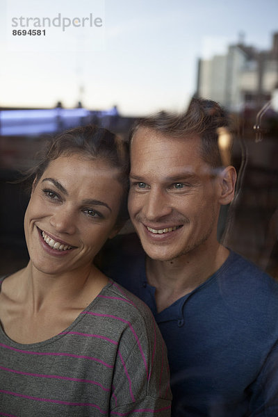 Porträt des lächelnden Paares hinter dem Fenster