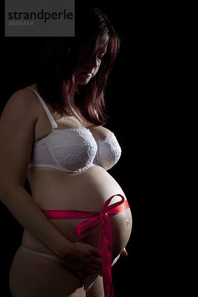Schwangere Frau mit Schleife um den Bauch