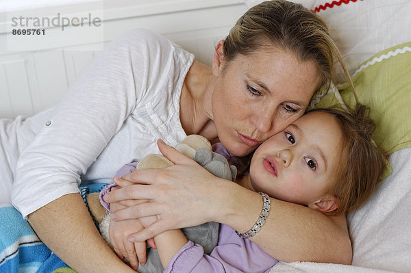 Mutter und Tochter kuscheln im Bett  umarmen sich