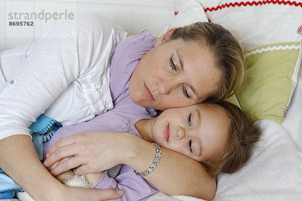 Mutter und Tochter kuscheln im Bett  umarmen sich