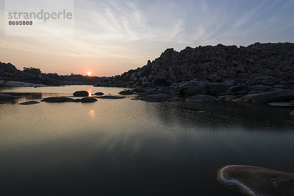 Sonnenuntergang über dem Fluss Tungabhadra und ein Teil der Ruinen von Vijayanagar  Hampi  Karnataka  Indien