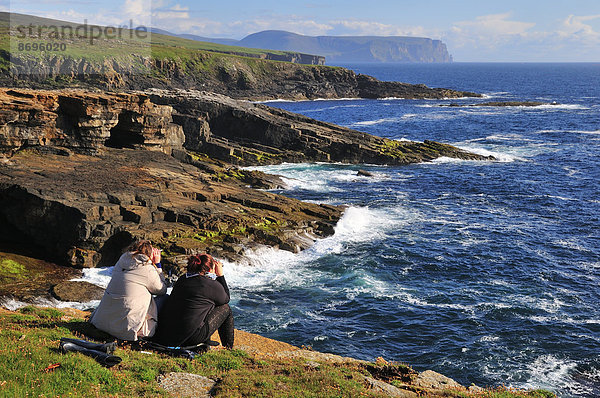 Zwei Touristinnen halten Ausschau mit Ferngläsern  Yesnaby  Mainland  Orkney  Schottland  Großbritannien