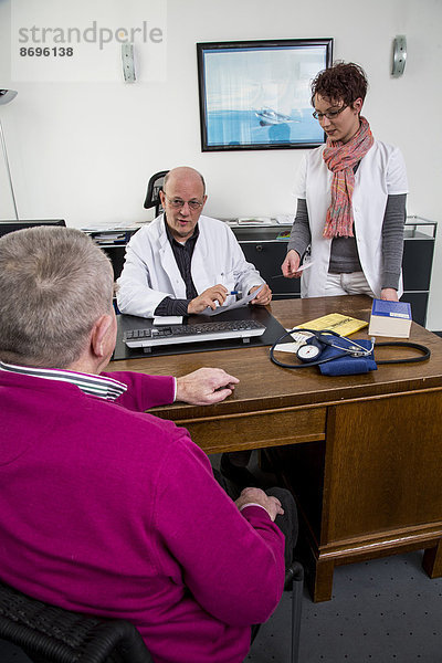 Arztpraxis  älterer Patient im Gespräch mit seinem Hausarzt  Sprechstundenhilfe  Deutschland