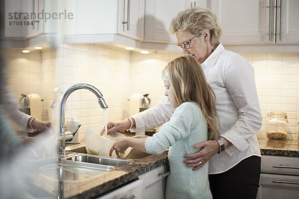Großmutter und Enkelin beim Gemüsewaschen in der Küche