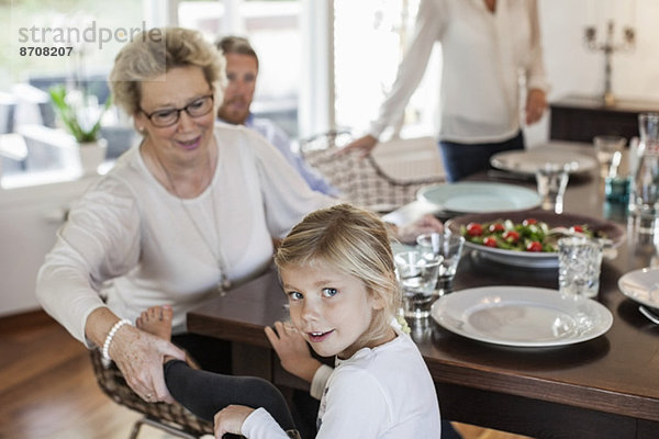 Porträt eines Mädchens  das mit seiner Familie am Esstisch sitzt.