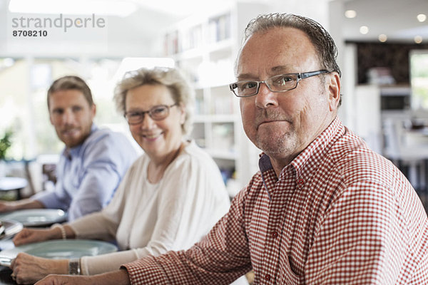 Porträt einer Zwei-Generationen-Familie  die am Esstisch sitzt.