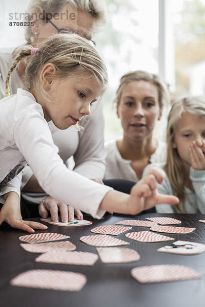 Mädchen spielen Kartenpuzzlespiel mit der Familie zu Hause