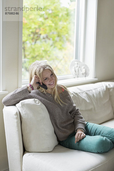 Teenager-Mädchen mit Handy beim Entspannen auf dem Sofa zu Hause