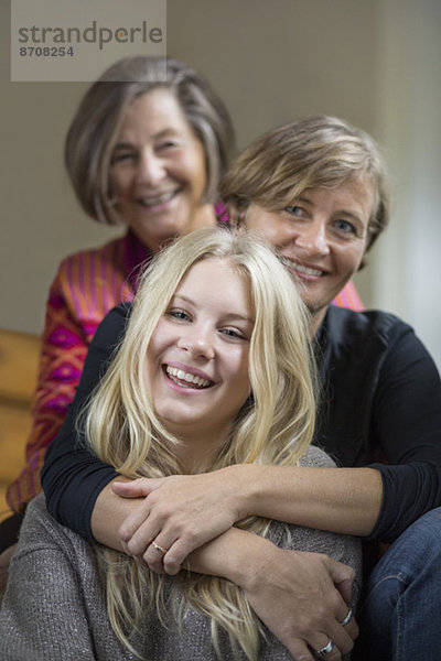 Porträt von drei Generationen von Frauen  die in einer Reihe zu Hause sitzen.