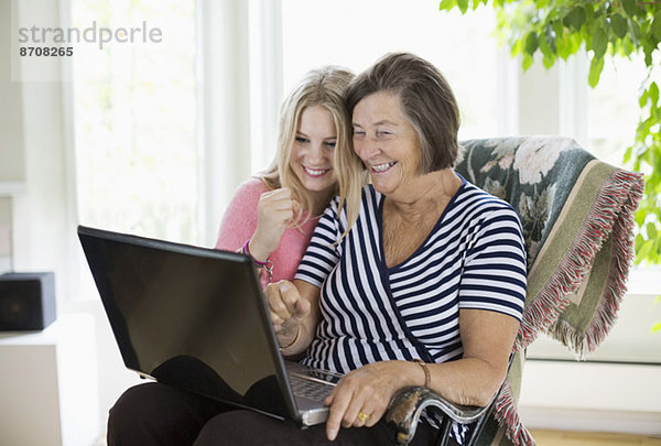 Glückliche Großmutter und Enkelin mit Laptop zu Hause