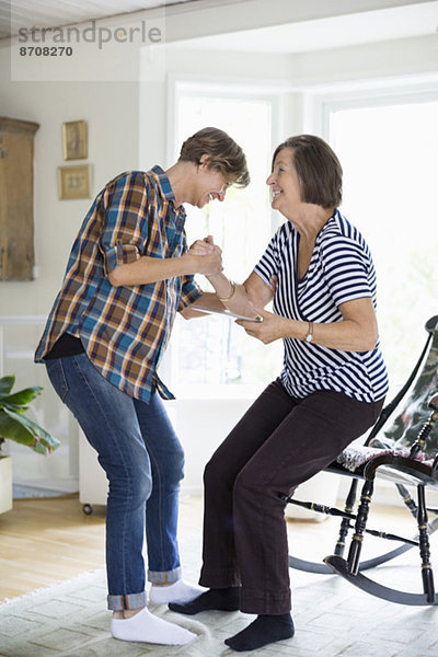 Reife Frau hilft Mutter beim Aufstehen vom Stuhl zu Hause