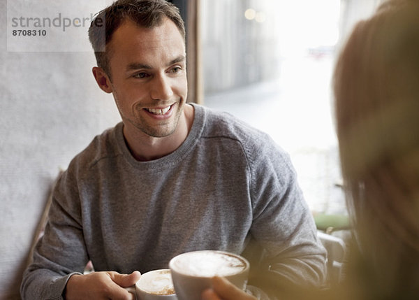 Junger Mann beim Kaffee mit Frau im Café