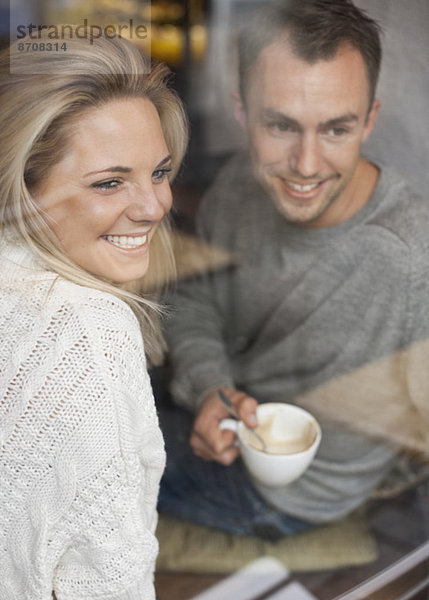 Glückliches Paar  das aus dem Caféfenster schaut und Kaffee trinkt.