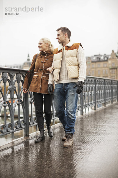 Volle Länge des jungen Paares  das auf der Brücke geht.