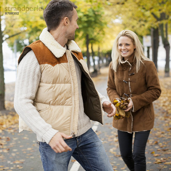 Verspieltes junges Paar auf der Straße im Herbst