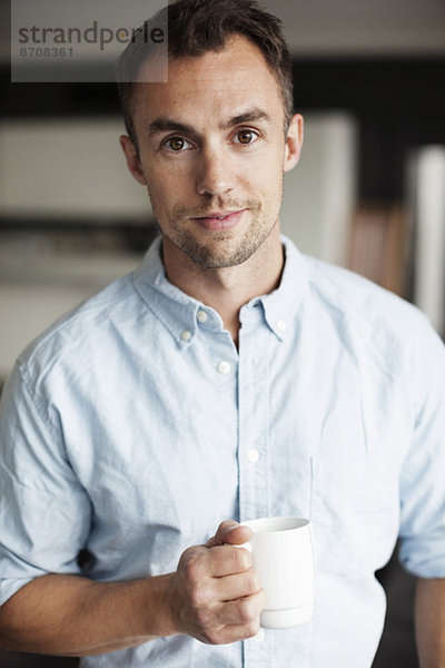 Porträt eines selbstbewussten Geschäftsmannes mit Kaffeetasse im Amt