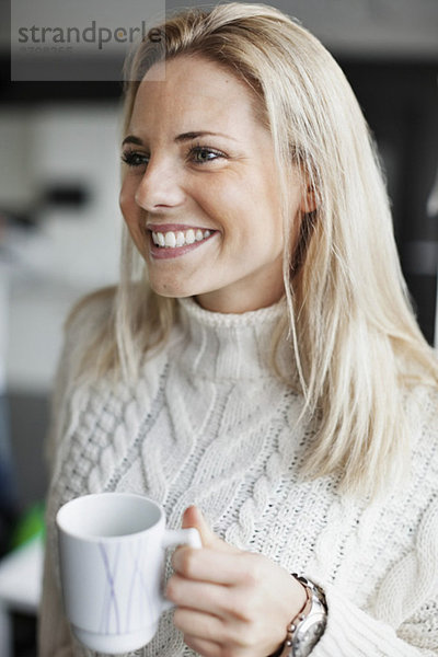 Lächelnde Geschäftsfrau mit Kaffeetasse im Büro