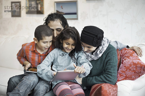 Muslimische Familie mit digitalem Tablett zusammen im Wohnzimmer