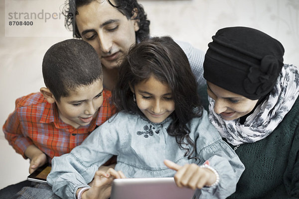 Muslimische Familie  die zu Hause gemeinsam digitale Tabletts benutzt