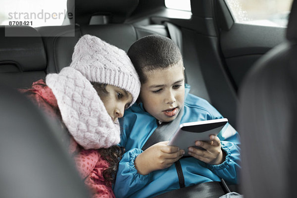 Geschwister mit digitalem Tablett im Auto