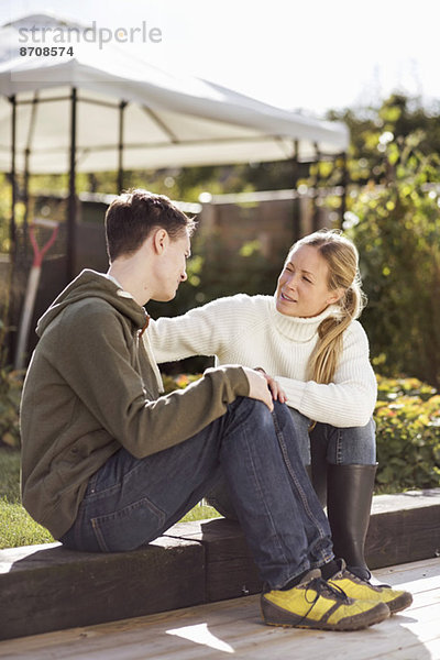 Mutter und Sohn beim Sitzen in einem Garten.