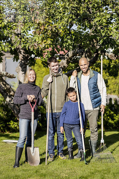 Porträt einer Familie mit Gartengeräten auf dem Hof