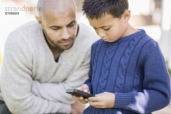 Vater und Sohn nutzen gemeinsam das Handy