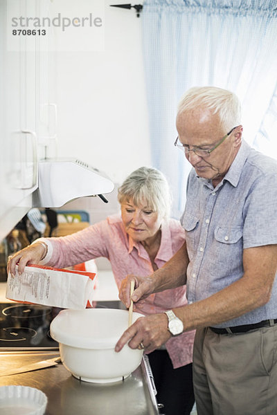 Seniorenpaar bei der Zubereitung des Essens an der Küchentheke